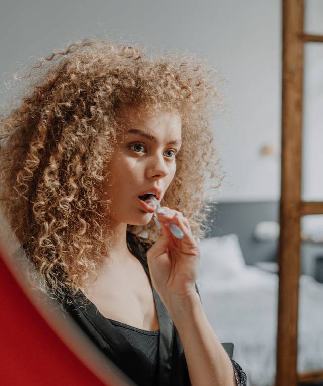 Frau putzt Ihre Zähne vor dem Spiegel